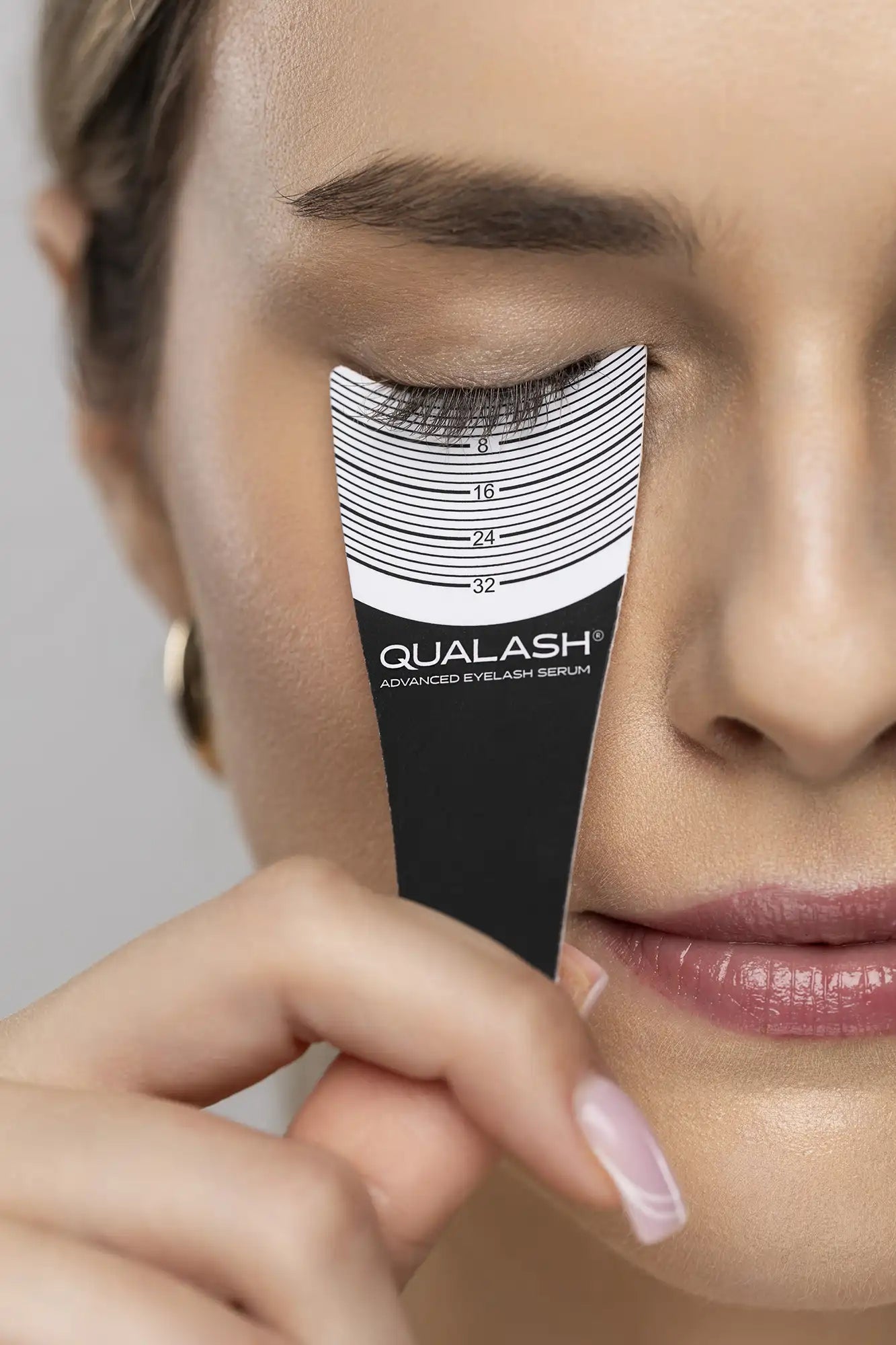Close-up of lashes measured with a lash ruler featuring the QUALASH logo